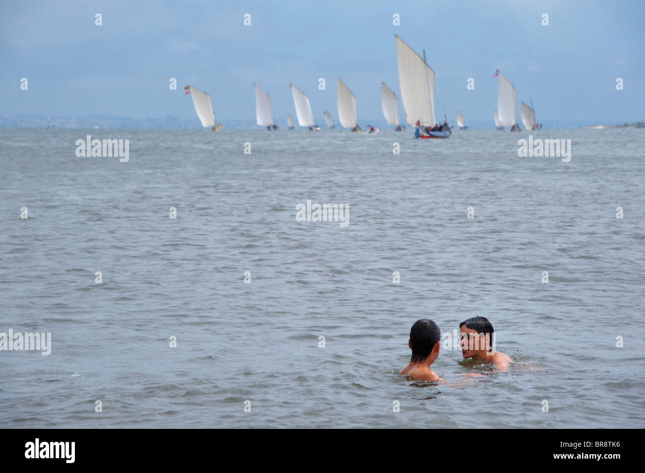 Deux adolescents nager près de voiliers traditionnels Moliceiro Aveiro, Portugal Banque D'Images
