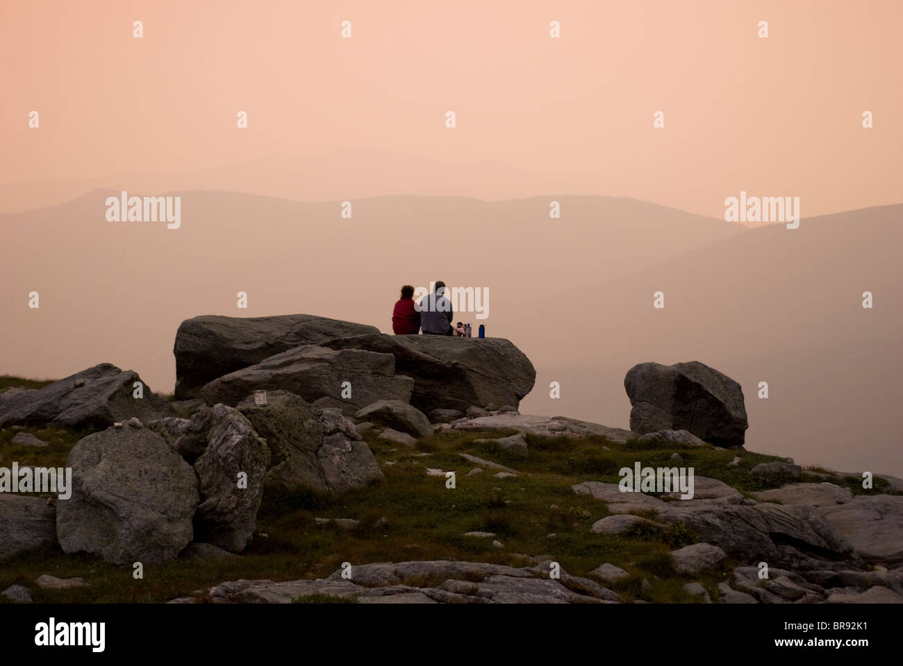 Un jeune couple assis sur un grand bouler en admirant le coucher du soleil sur l'élection présidentielle s'étend sur le mont Washington au New Hampshire. Banque D'Images