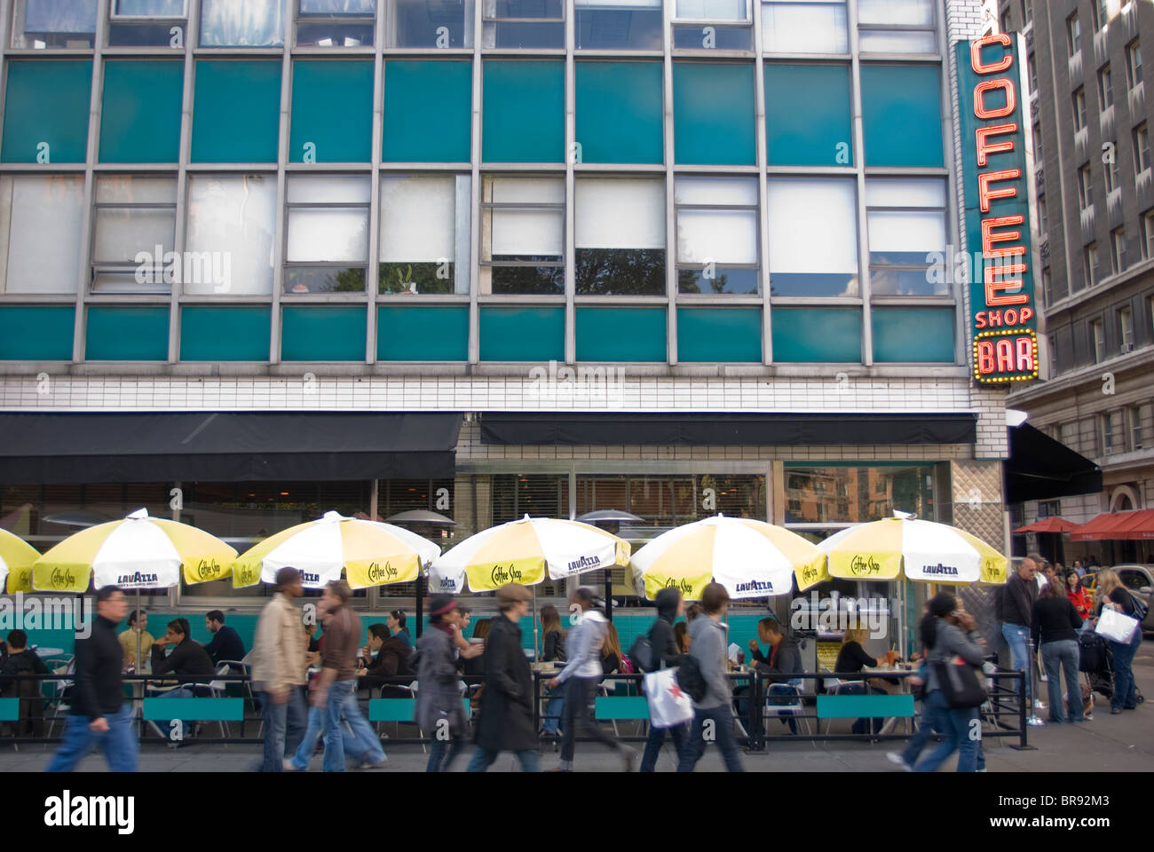 Les piétons passé l'enseigne au néon jaune et des parasols de la Coffee Shop Bar à Union Square. New York (NY). Banque D'Images