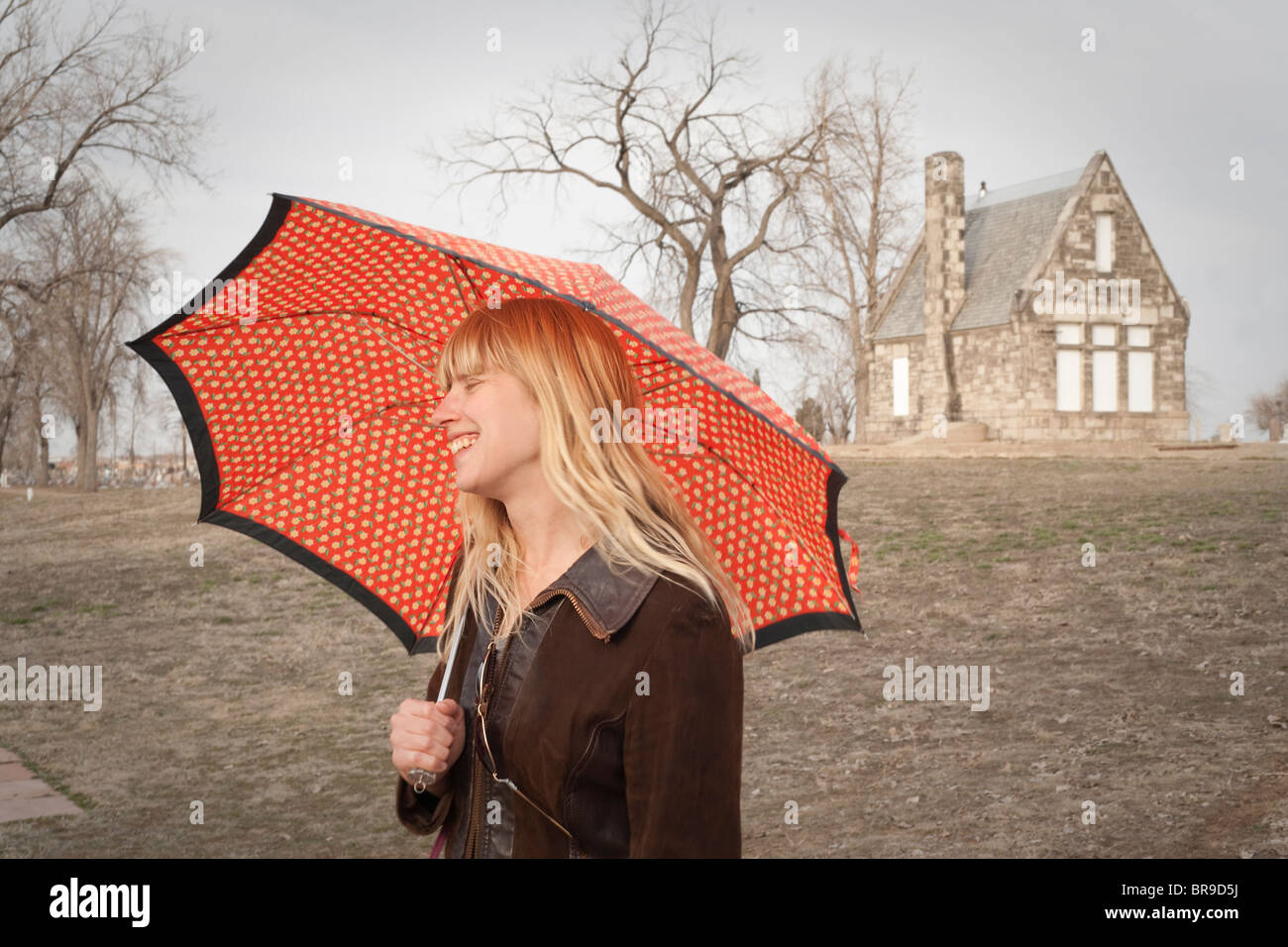 Une blonde femme avec parapluie à l'extérieur de la chapelle en pierre Banque D'Images