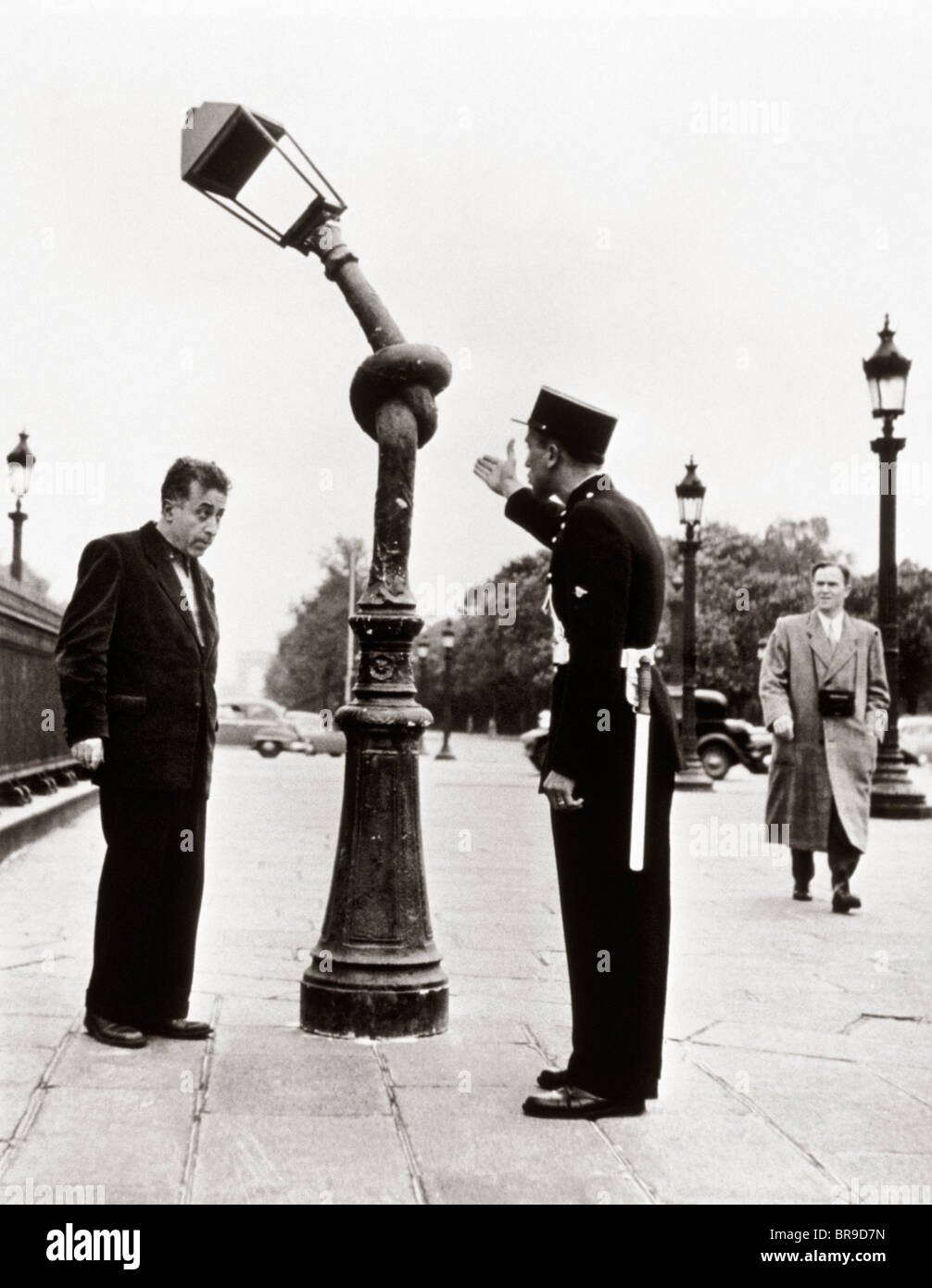 1950 GENDARME FRANÇAIS DRÔLE HOMME accusant d'attacher dans un noeud de la LAMPE DE RUE Banque D'Images