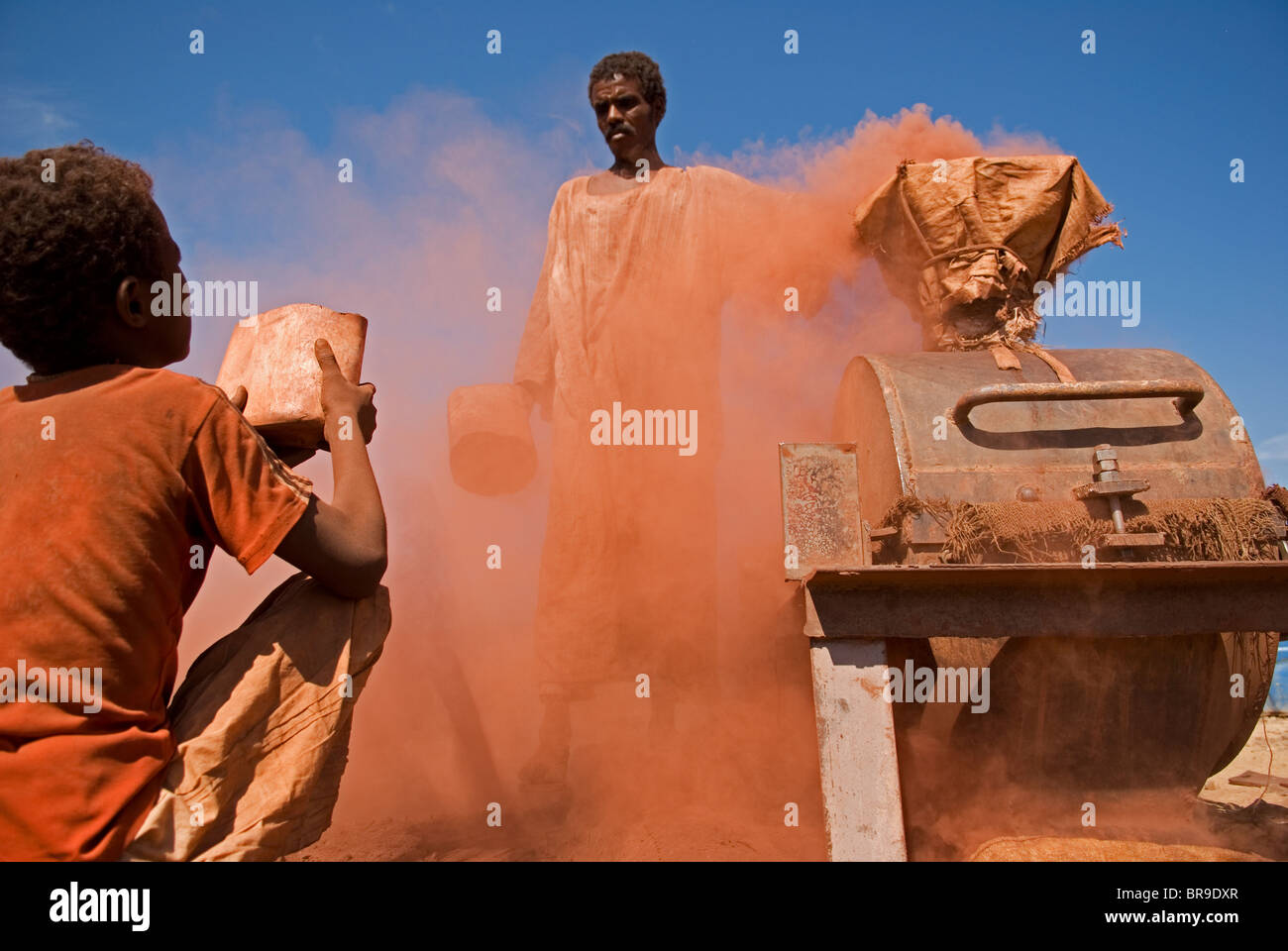 Un garçon contribue à écraser des pierres dans un moulin en pierre spécial au Soudan. Banque D'Images