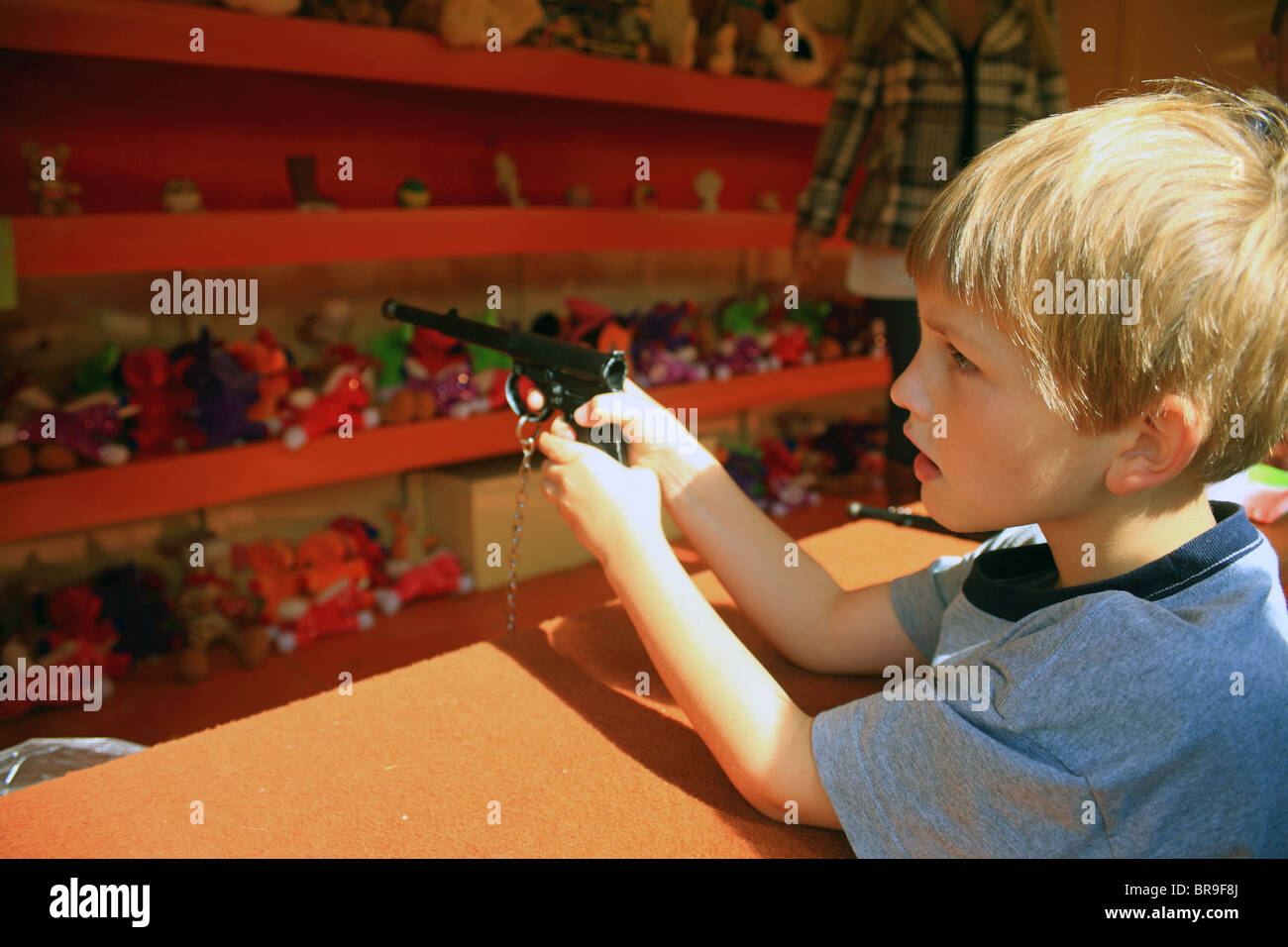 Garçon avec un pistolet de tir dans un jeu d'arcade à Challock Goose Fair, Challock, Ashford, Kent, Angleterre, Royaume-Uni, Europe Banque D'Images