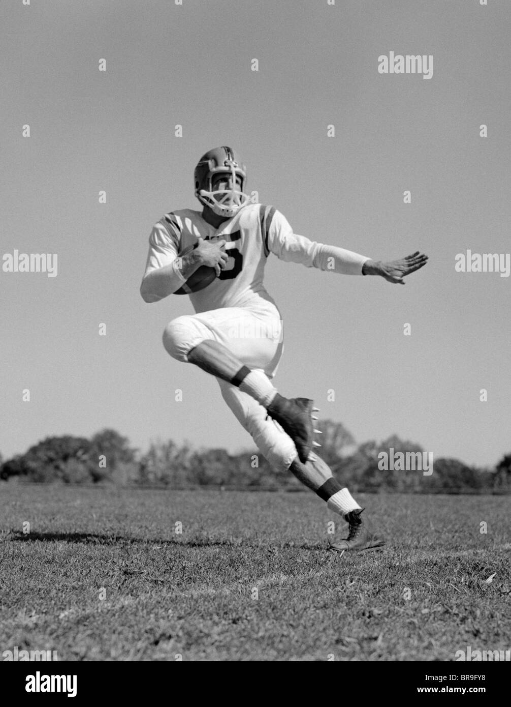 1960 JEUNE HOMME FOOTBALL PLAYER RUNNING WITH BALL Banque D'Images