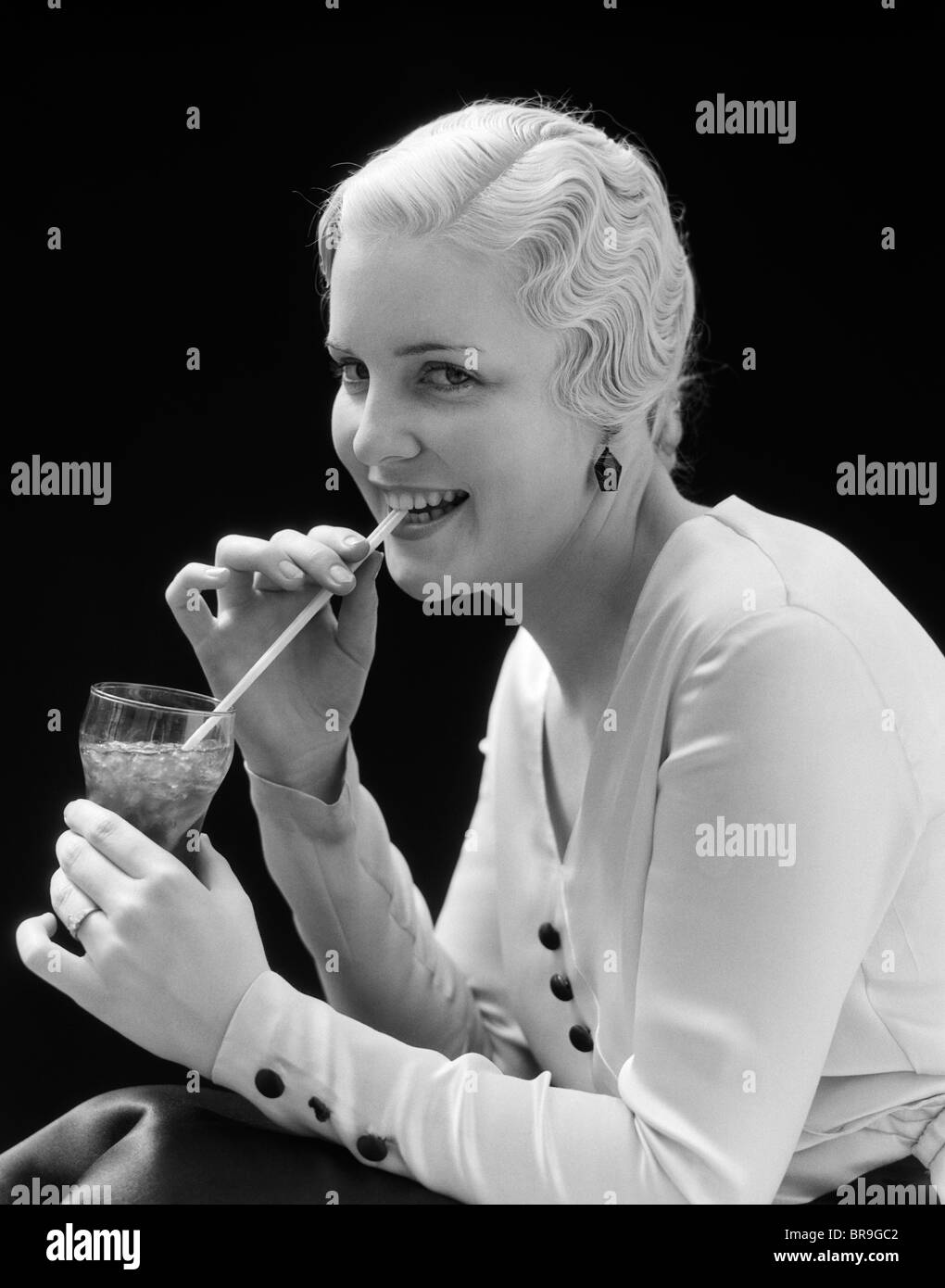 1930 BLONDE WOMAN DRINKING SODA AVEC UNE PAILLE Banque D'Images