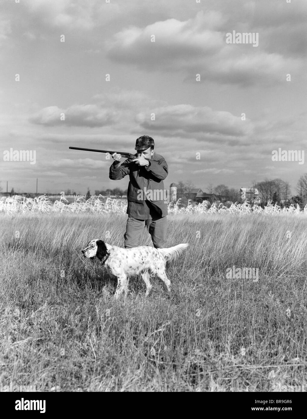 Années 1930 Années 1940 LA CHASSE AUX OISEAUX DE L'HOMME SUR LE TERRAIN AVEC LE CHIEN DE FUSIL VISANT Banque D'Images