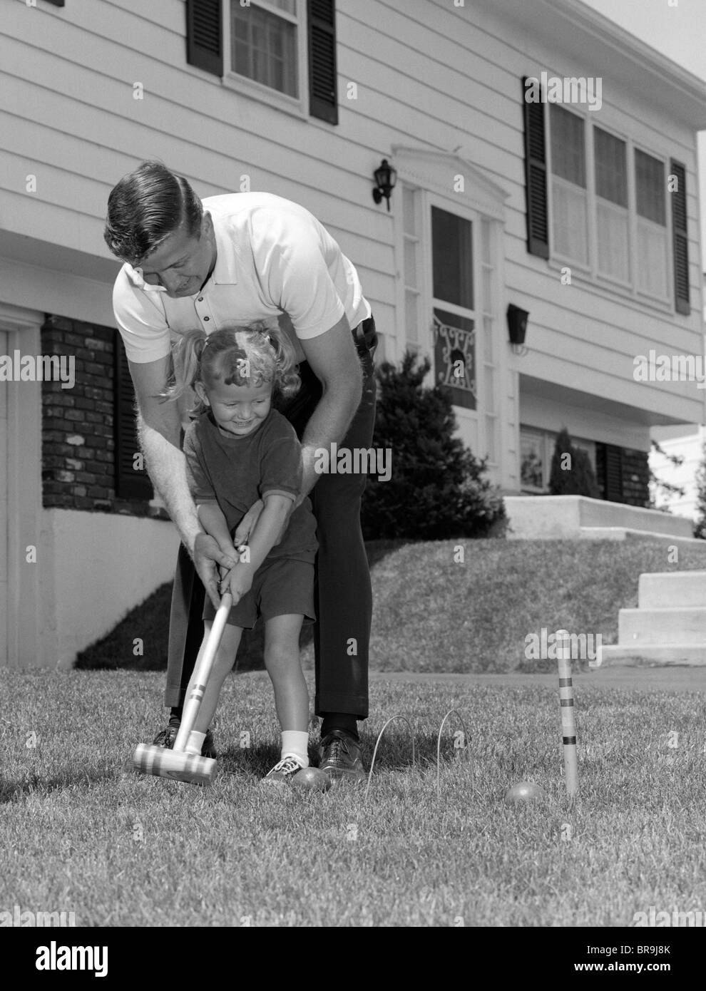 1960 PÈRE ET FILLE JOUER AU CROQUET DANS LE JARDIN Banque D'Images