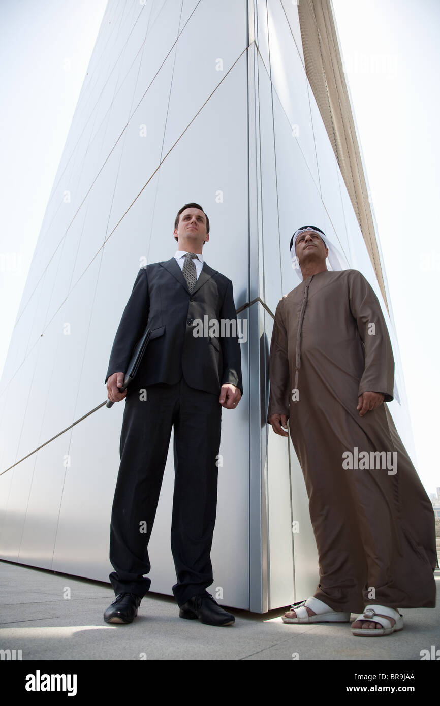 Les hommes d'affaires de l'Ouest et du Moyen-Orient à l'extérieur du bâtiment moderne Banque D'Images