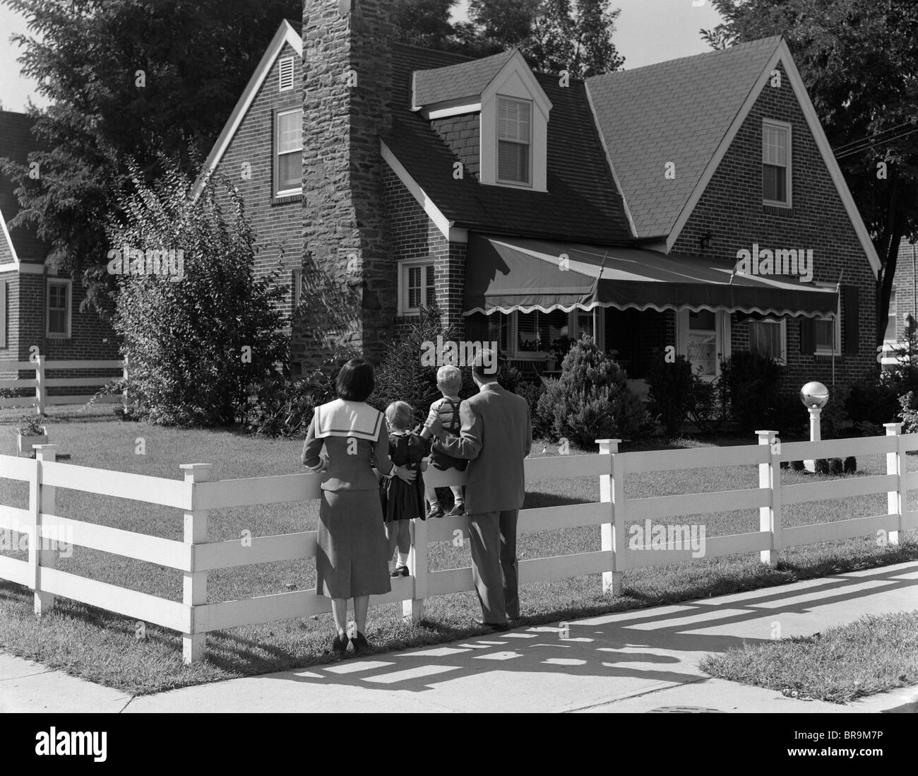 1950 FAMILY clôture blanche à la maison de brique à Banque D'Images