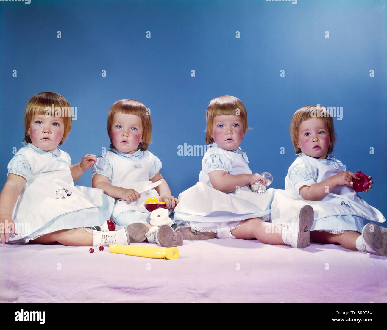 Années 1950 Années 1960 PORTRAIT DE QUADRUPLÉS 4 Filles aux cheveux rouges portant des robes ASSIS DANS UNE RANGÉE Banque D'Images