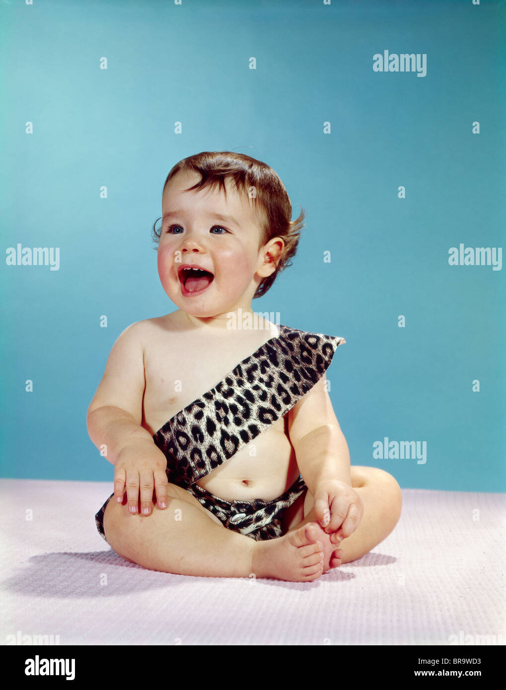 1960 rire heureux d'ouvrir grand la bouche de bébé LÉOPARD PORTANT COSTUME Homme des cavernes TARZAN Banque D'Images