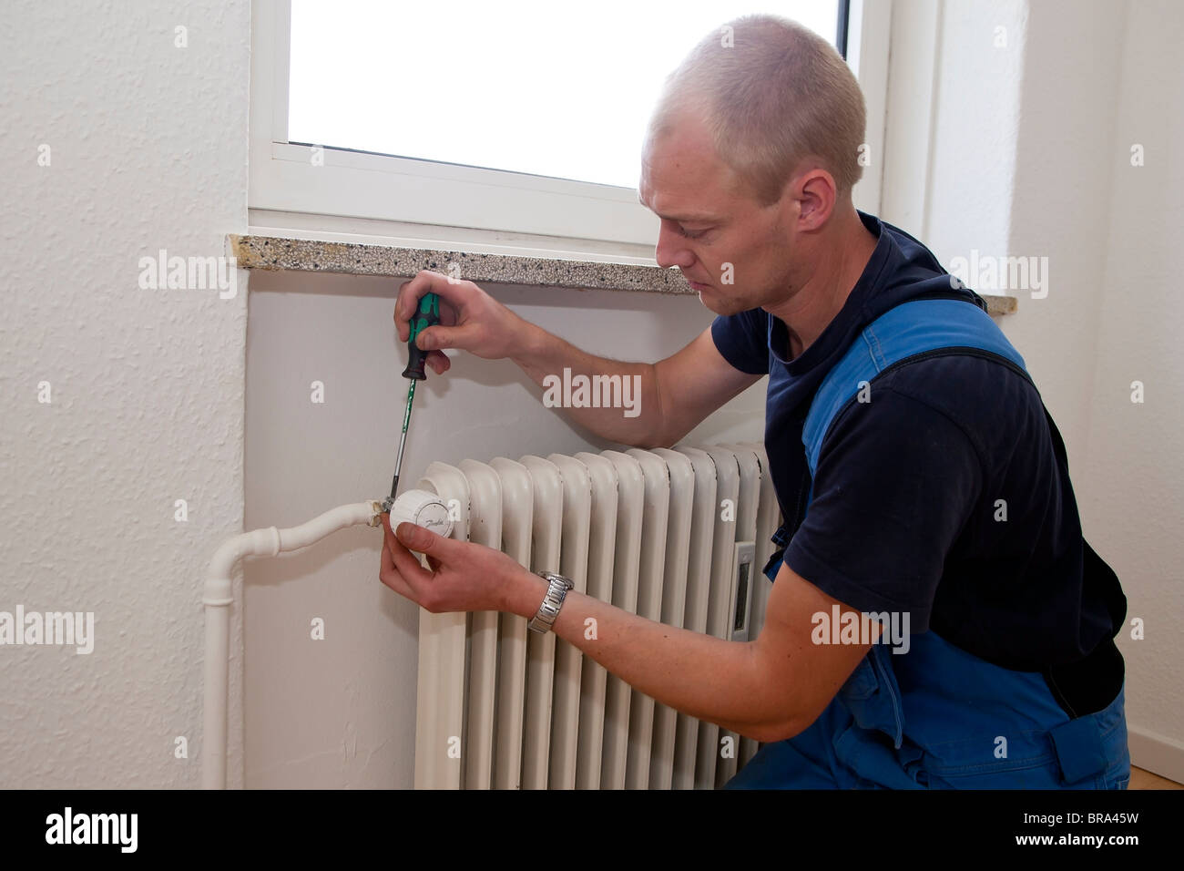 Technicien en chauffage et sanitaire réparer un robinet de radiateur thermostatiques Banque D'Images