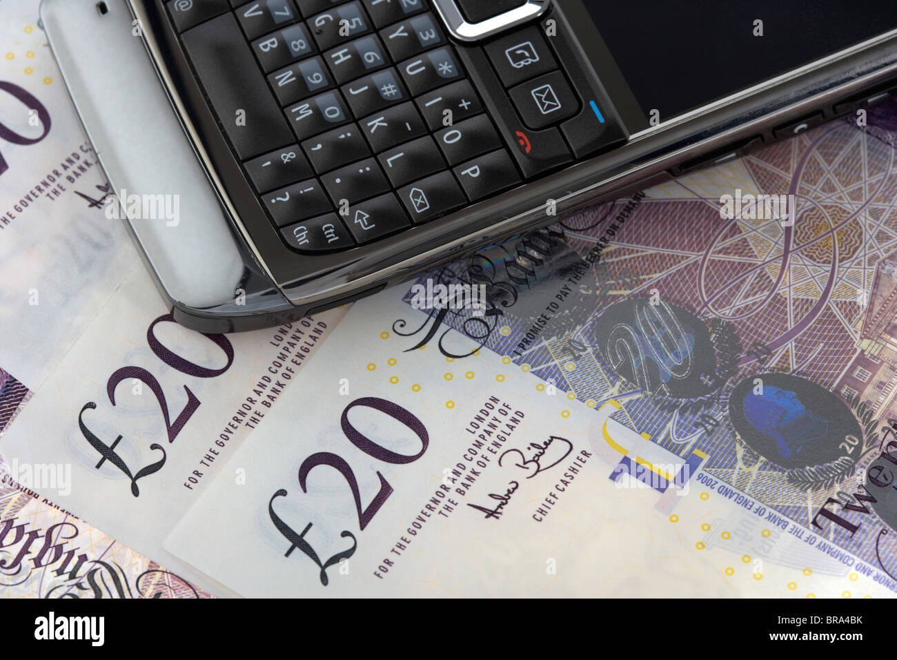 Mobile cell phone smartphone sur un tas de billets de 20 livres sterling Banque D'Images