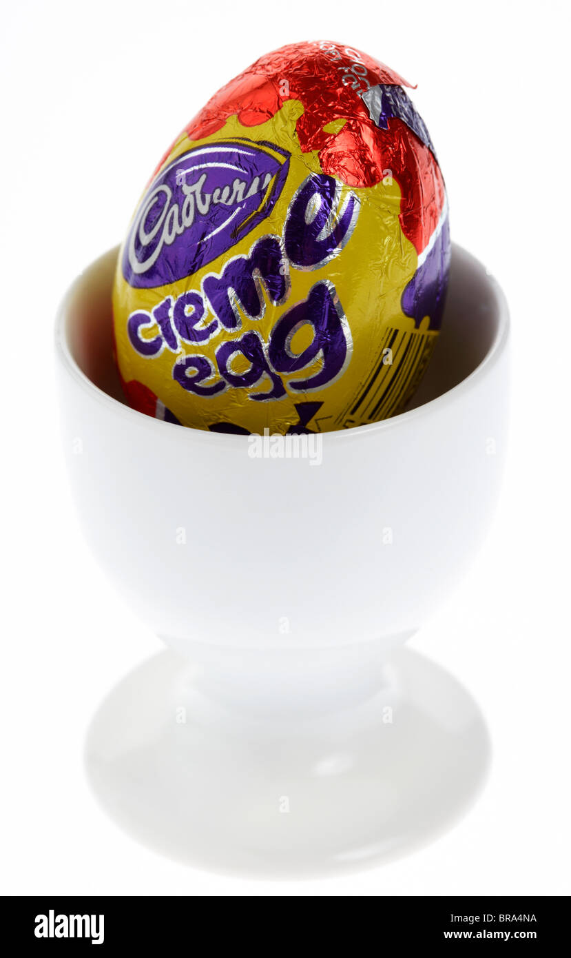 Cadburys creme egg in a white egg cup sur fond blanc Banque D'Images