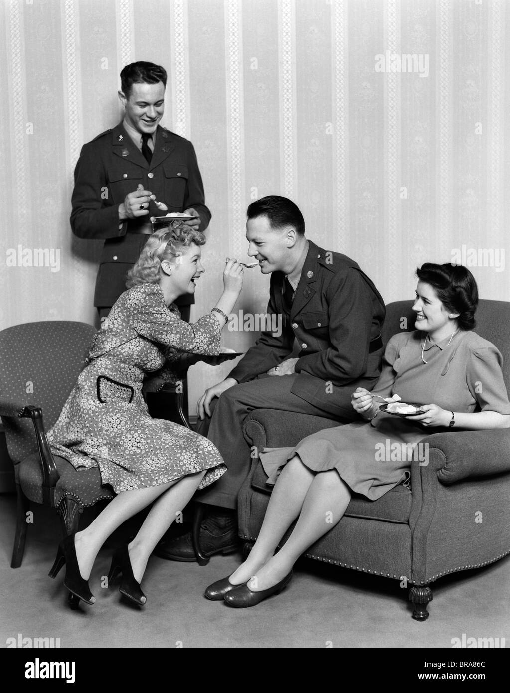 1940 COUPLES EATING DESSERT LES HOMMES EN UNIFORME FEMME HOMME ALIMENTATION cuillère Banque D'Images