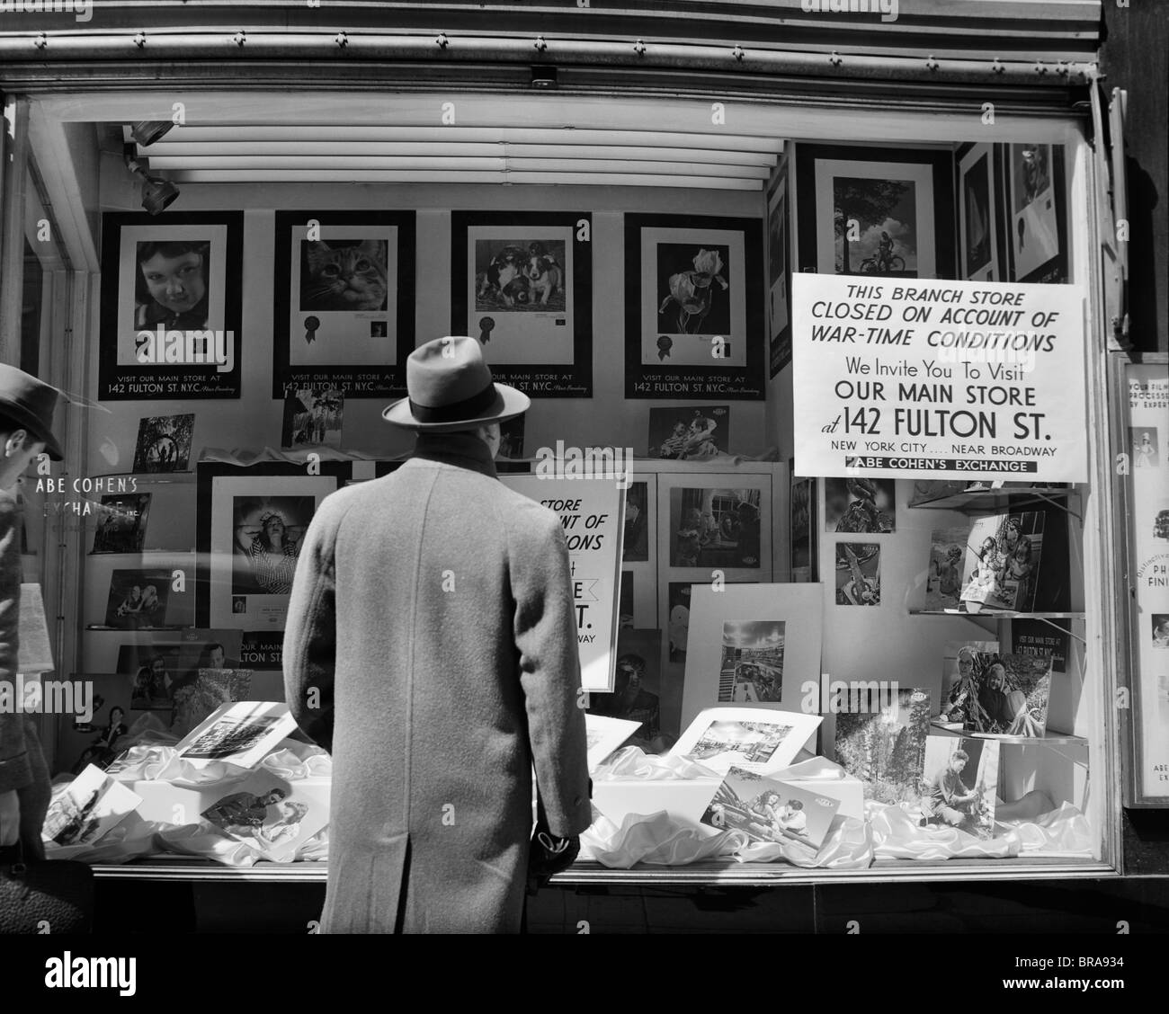 1940 L'HOMME À LA FENÊTRE DE MAGASIN DE LA VILLE DE NEW YORK AVEC SIGNE EXPLIQUANT FERMÉE EN RAISON DE CONDITIONS DU TEMPS DE GUERRE Banque D'Images