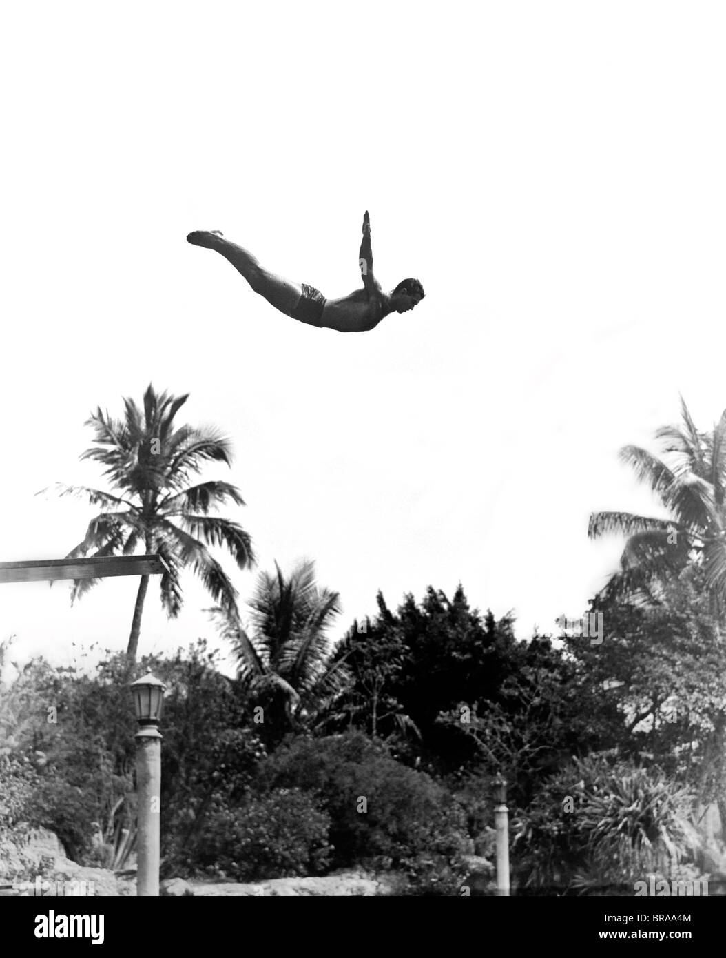 1940 L'HOMME Le point milieu de l'air bras en sautant de PLONGEOIR EN EXTÉRIEURE Banque D'Images