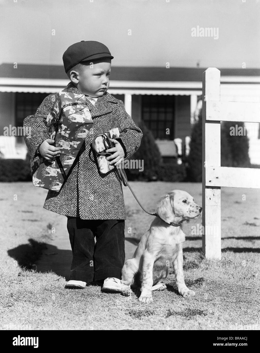 1940 garçon avec chiot en laisse HOLDING CHRISTMAS PRESENT Banque D'Images