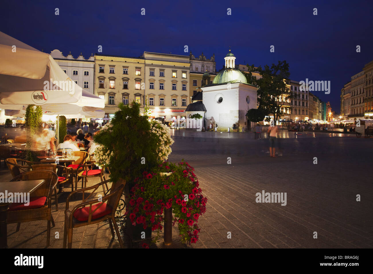 Dans les cafés en plein air place du marché (Rynek Glowny) avec l'église de saint Adalbert en arrière-plan, l'UNESCO, Cracovie, Pologne Banque D'Images
