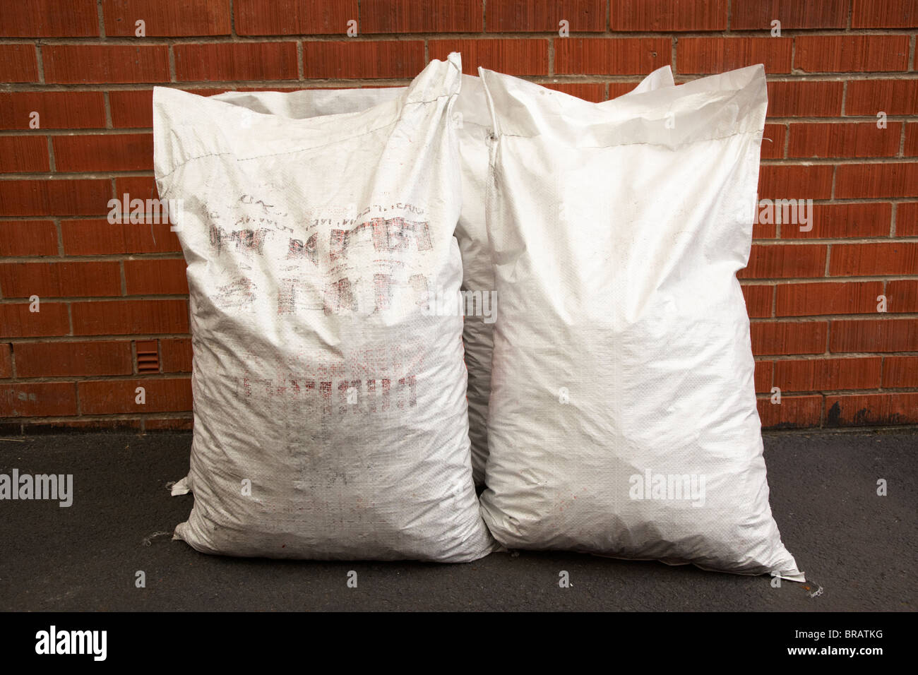 Sacs de charbon en sacs de 25 kg de plastique livré appuyé contre un mur de la maison en brique rouge au Royaume-Uni Banque D'Images