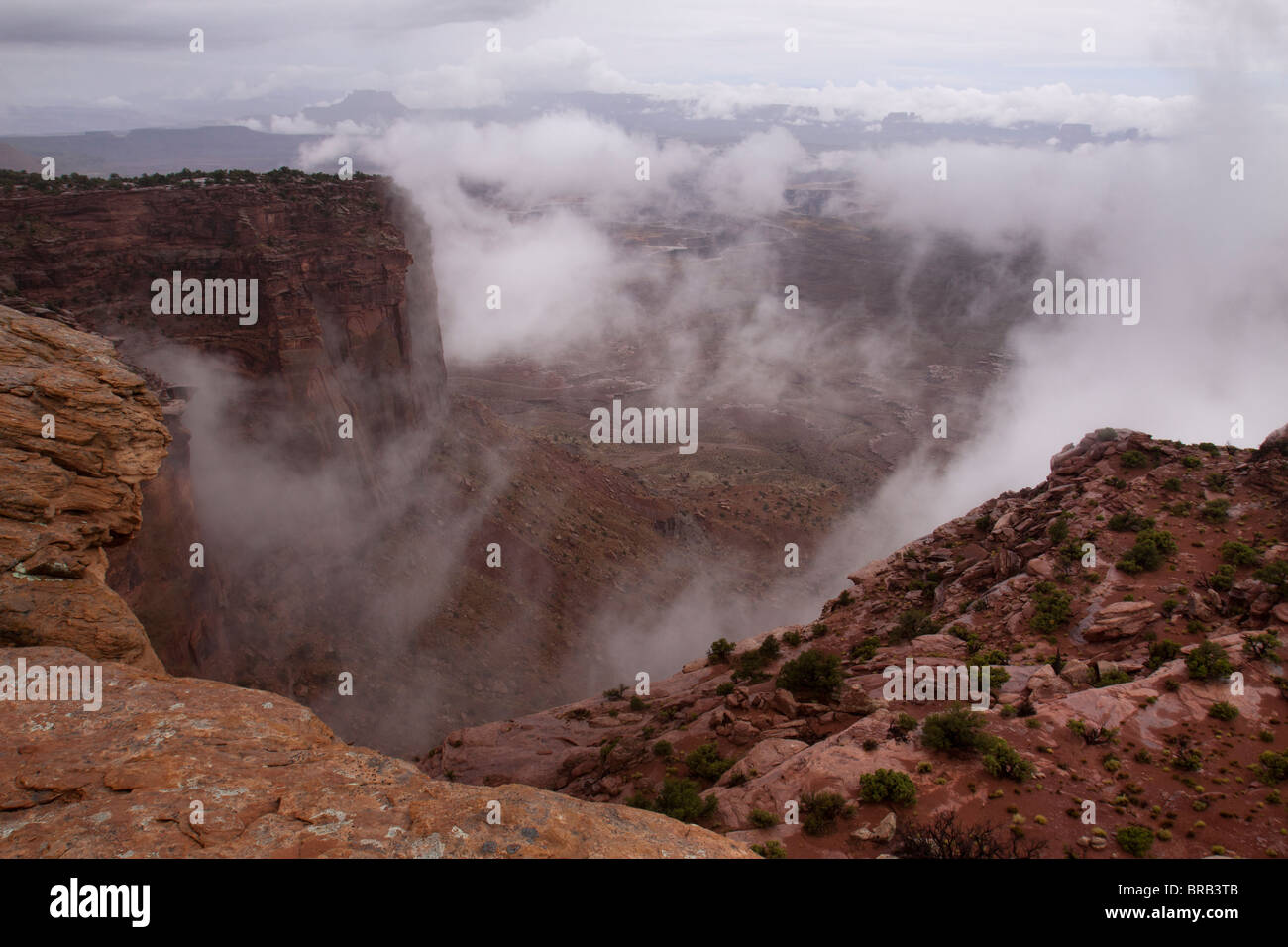 Les nuages de tempête formant et remplissage du grand canyon au-delà des falaises au Candlestick Tower donnent sur la région de Canyonlands National Park, Utah Banque D'Images