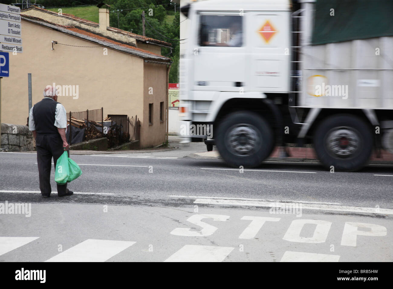 Vieil homme avec son shopping traverse route de martinet de Cerdanya près de la Seu d'Urgell en Espagne Pyrénées Banque D'Images