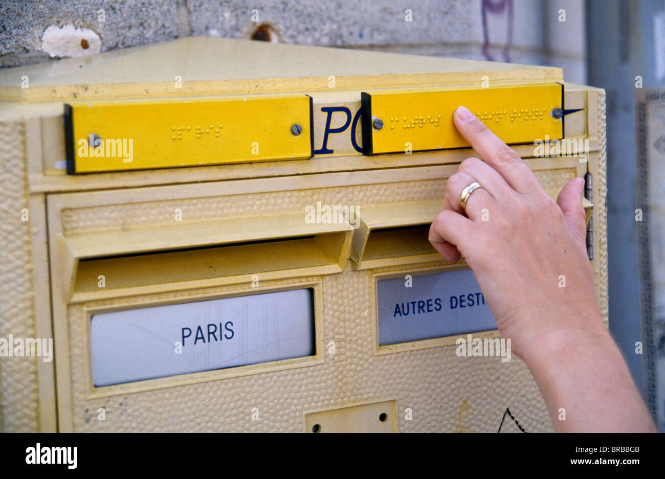 France, Ile de France, Paris, lettre Postbox avec inscription en braille pour les aveugles et une femme part de la lecture du texte a soulevé. Banque D'Images