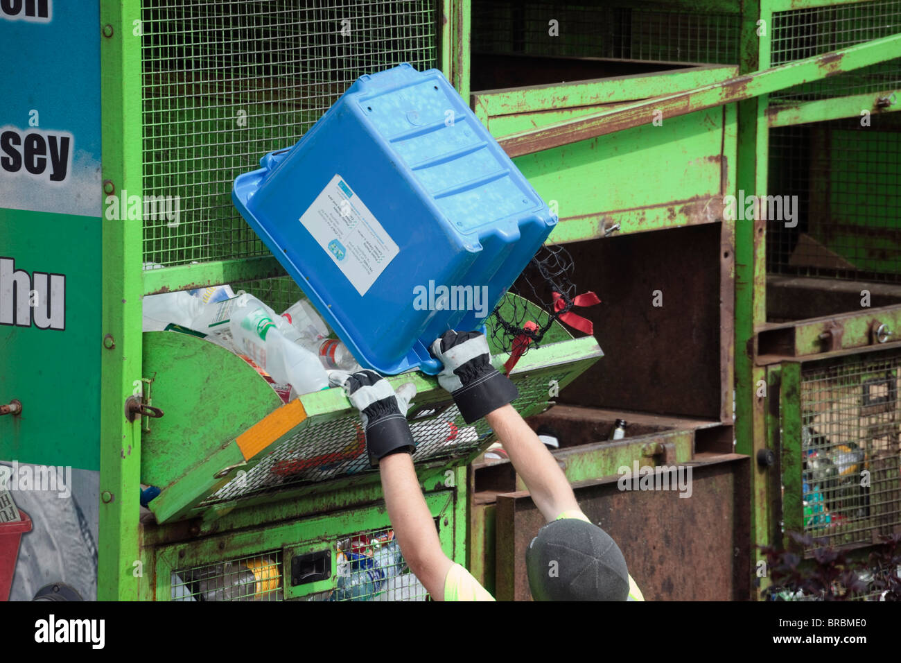 Recyclage Collecte ouvrier fort de vider des bouteilles de plastique en chariot dans le cadre du schéma de gestion des déchets. Anglesey au nord du Pays de Galles UK Banque D'Images