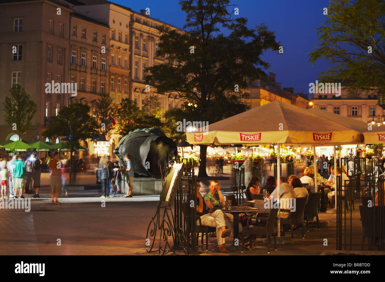 Dans les cafés en plein air place du marché (Rynek Glowny) au crépuscule, Cracovie, Pologne Banque D'Images