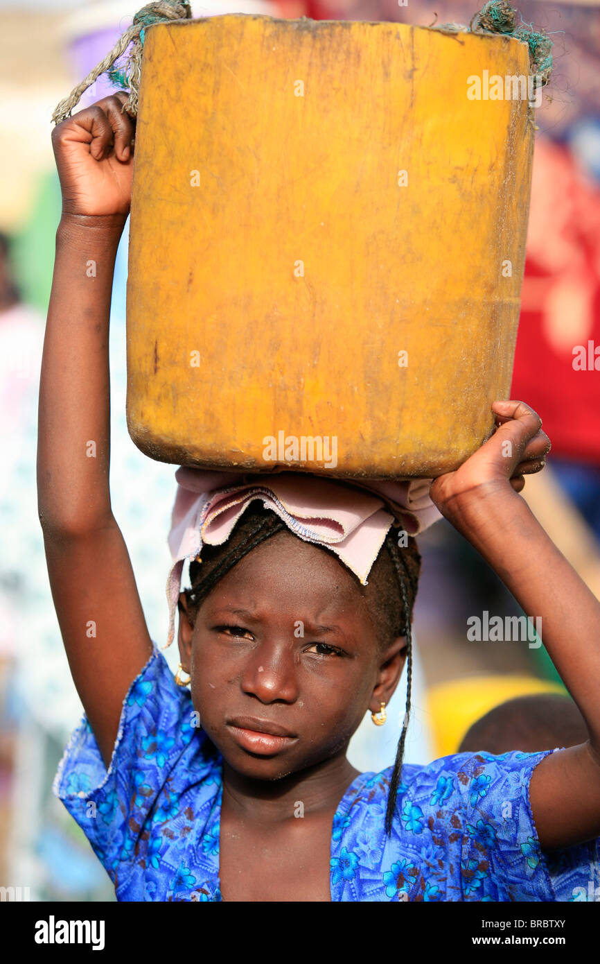Jeune fille transportant une lourde charge, Saint Louis, Sénégal, Afrique de l'Ouest Banque D'Images