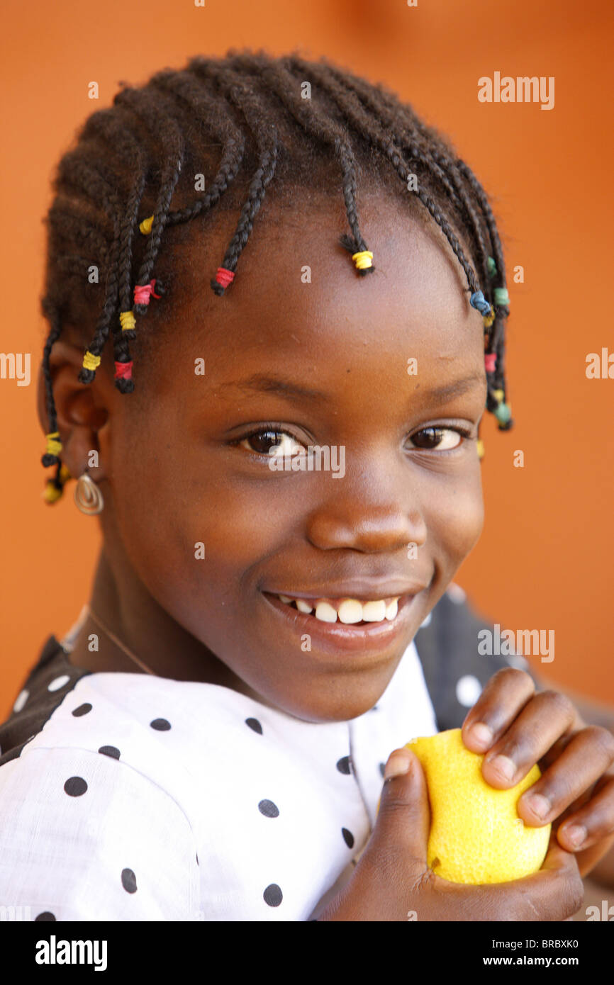 African girl eating an orange, Lomé, Togo, Afrique de l'Ouest Banque D'Images