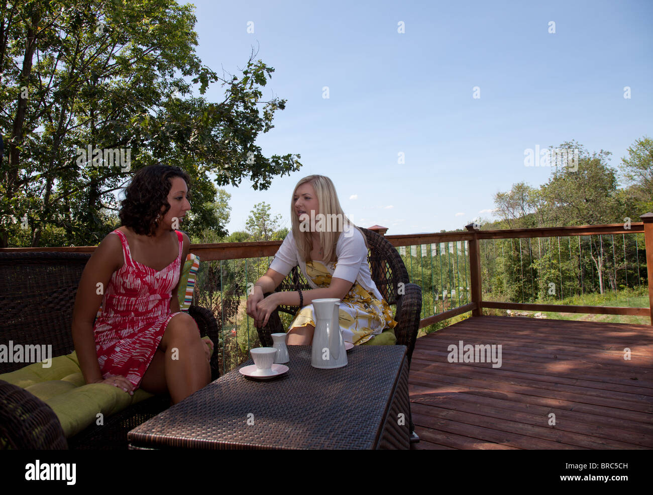 Deux jeunes femmes partageant un café ou un thé à l'extérieur sur le porche Banque D'Images