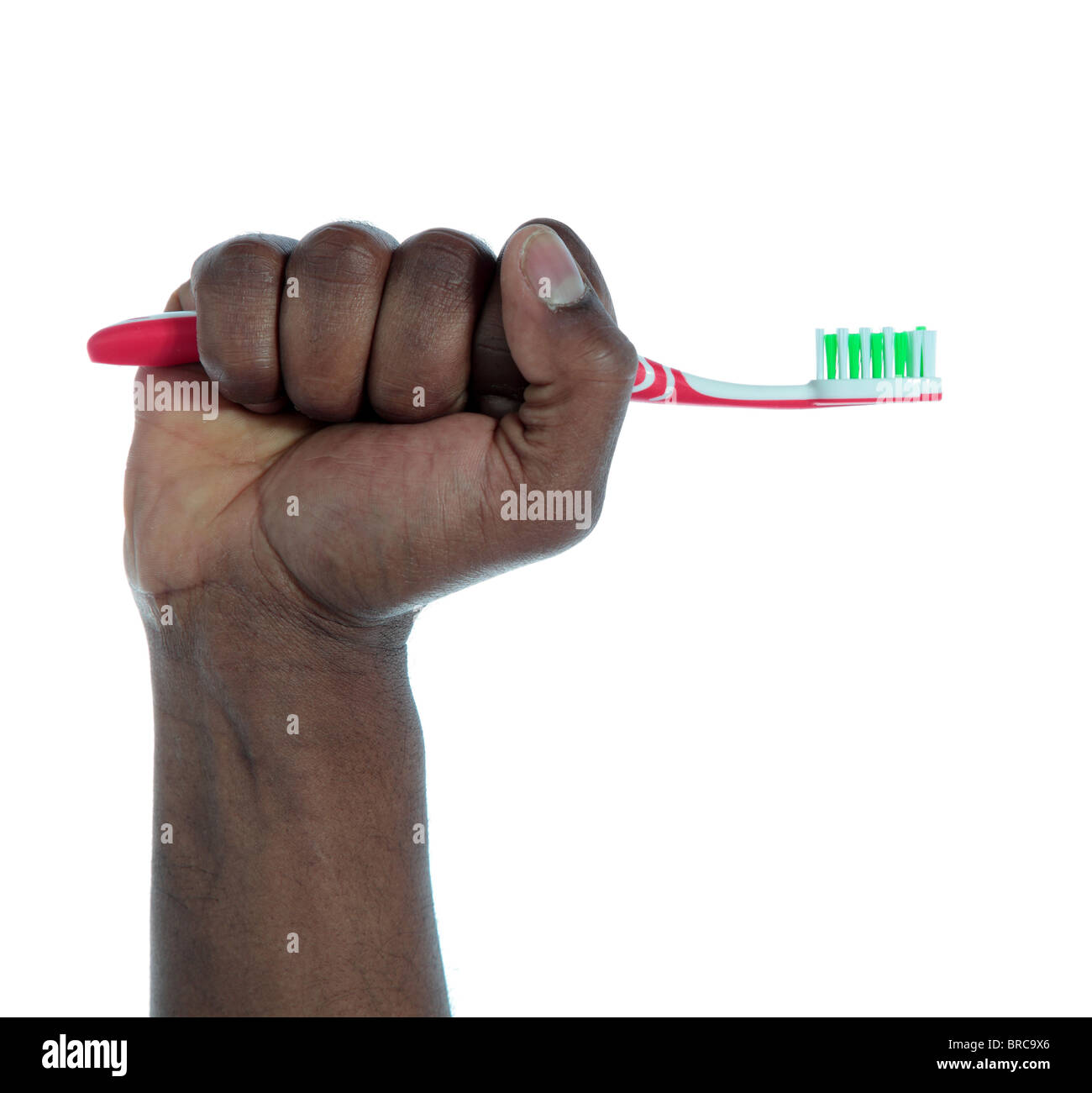 La peau foncée d'une main tenant une brosse à dents. Le tout sur fond blanc. Banque D'Images