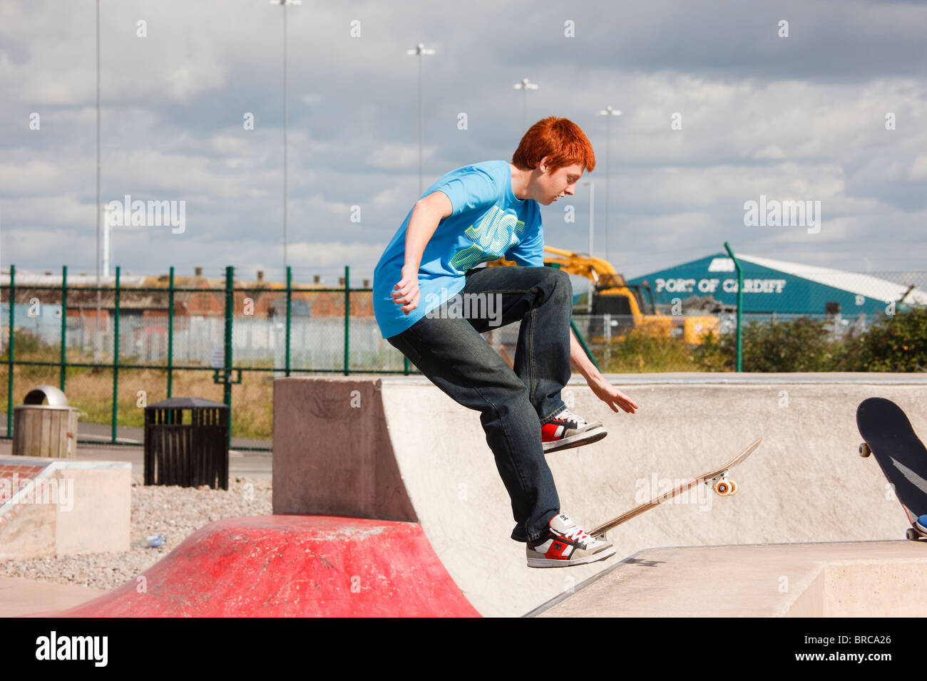 Teenage boy skateboarding en Skate Plaza nouveau planchodrome. Barrage de Cardiff Bay Park, Cardiff, Glamorgan, Pays de Galles, Royaume-Uni Banque D'Images