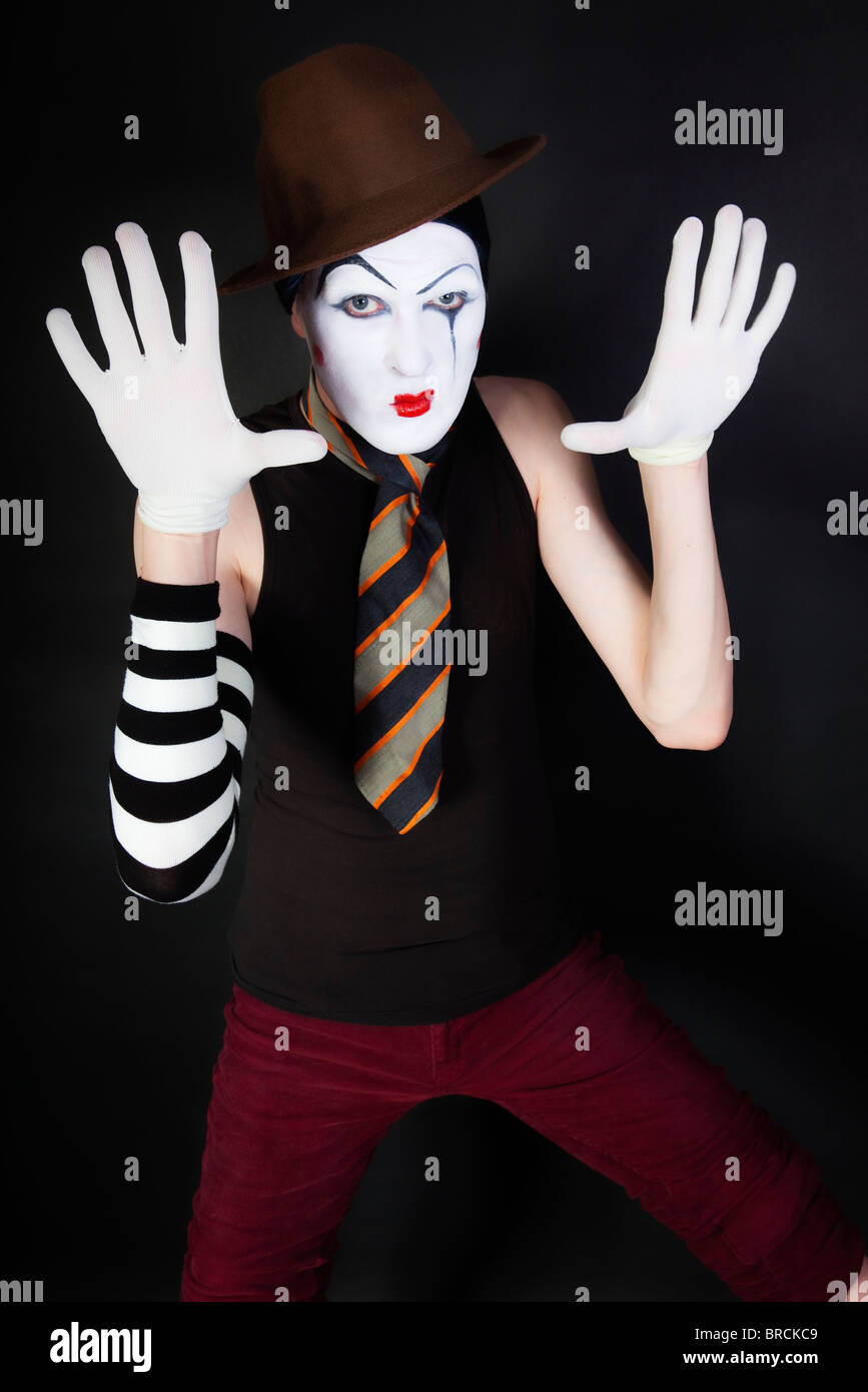 Funny mime sur un fond noir avec des gants blancs et un chapeau brun Banque D'Images