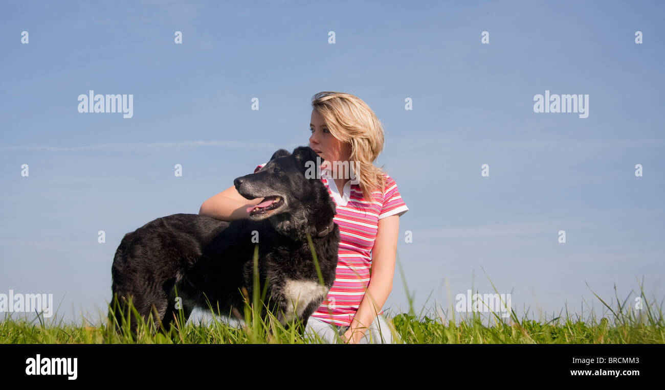 Jolie jeune femme et son chien à la recherche dans la distance tout en appréciant assis sur une des portes de l'été ensoleillé jour. Banque D'Images