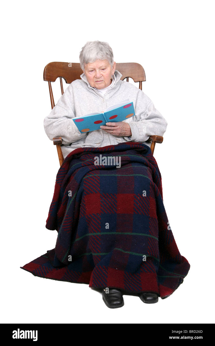 Une vieille femme adulte assis dans un rocking-chair en lisant un livre Banque D'Images