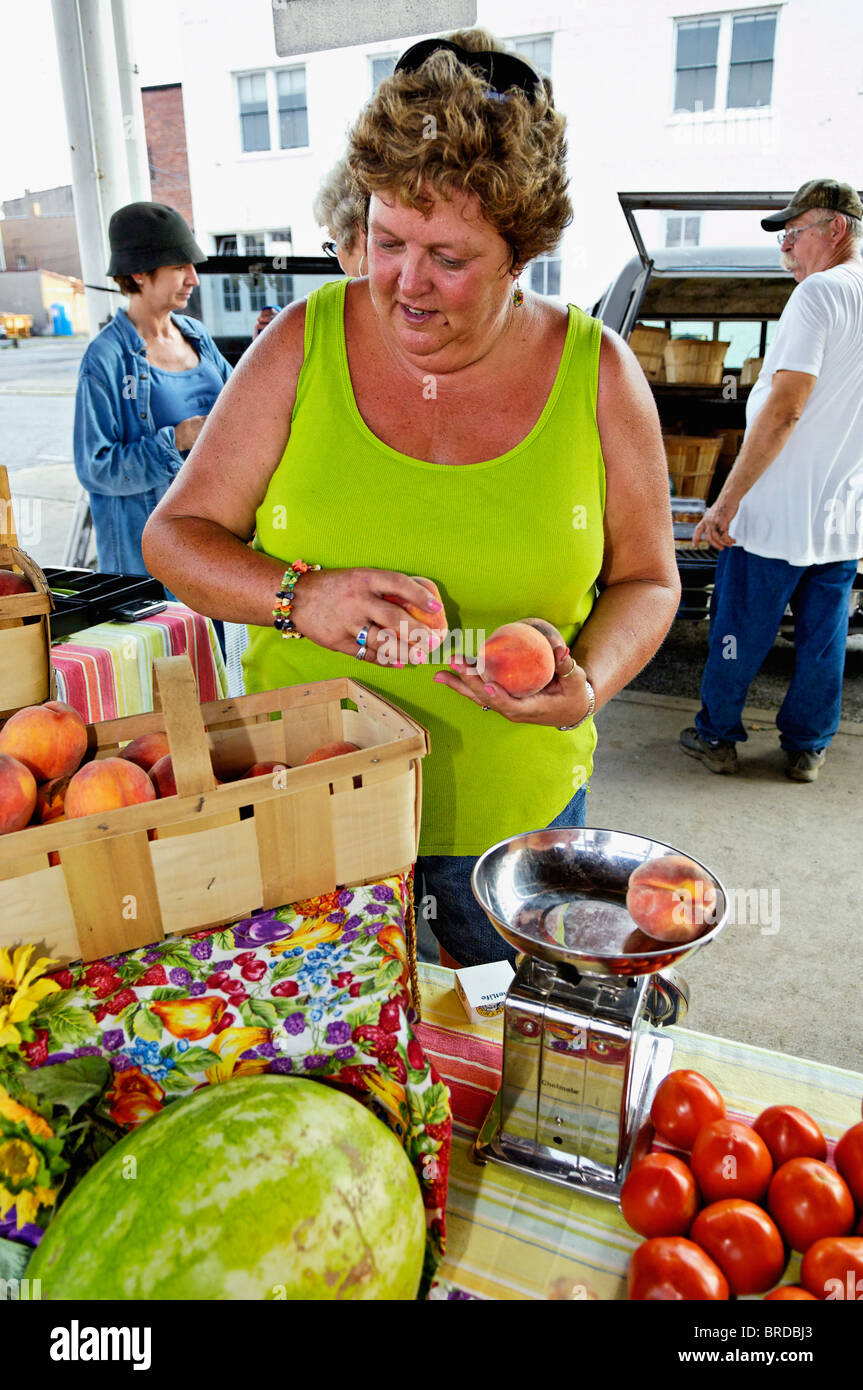 Femme pesant Pêches fraîches au milieu d'autres produits à Farmers Market à New Albany, Indiana Banque D'Images