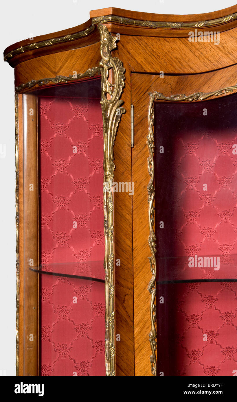 Une armoire d'affichage en serpentine du décor de salon, attribuée à l'Atelier Gambs, Saint-Pétersbourg, 1846. Placage de bois tropical, verre, finitions en bronze doré et brocart rouge avec décoration en fleur relevée. Les portes pivotantes et les surfaces latérales sont dotées d'inserts en verre, de deux étagères en verre et d'une étagère en bois couverte de brocart. Un pied avec l'étiquette d'inventaire 'ON' de Grand Duchesse Olga Nikolaevna, attaché à l'intérieur de l'étiquette 'H.V.v.W. G.v.R.' de la duchesse Vera de Württemberg, Grande duchesse de Russie. Restauration ancienne de la partie arrière. 173,5 x 99 x 40 cm. Provenance: Grand, Banque D'Images