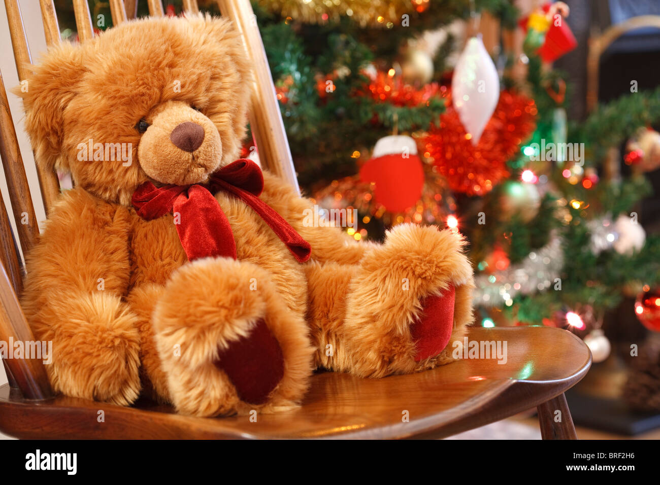 Scène de Noël traditionnel avec un ours en peluche sur une chaise face à un arbre de Noël Banque D'Images