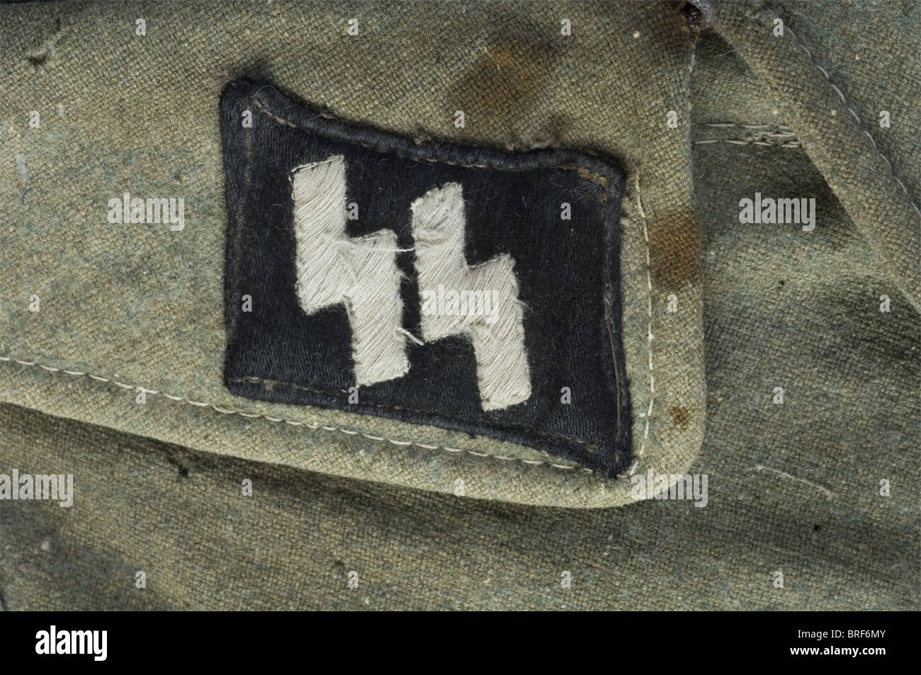 Schutzstalof, Vareuse de STURMMANN de la Götz von Berlichingen, comportant ses pièces de col, son chevron de bras de grade et son aigle de bras. Pates d'épeules absentes. Feldgrau textile, intégré en soie artificielle, pattes de col tissées machine, chevron feldgrau, aigle et bande de bras 'Bévo'. Nombeux impacts de mites, de déchirres et traces de sang au col. La banque de bras est le très abimée sur les capitaines endoses. Cette vareuse est l'une des seules connes qui soir, sans contest, montée entièrement d'origine. Elle a été créée dans la région de Norma, Banque D'Images