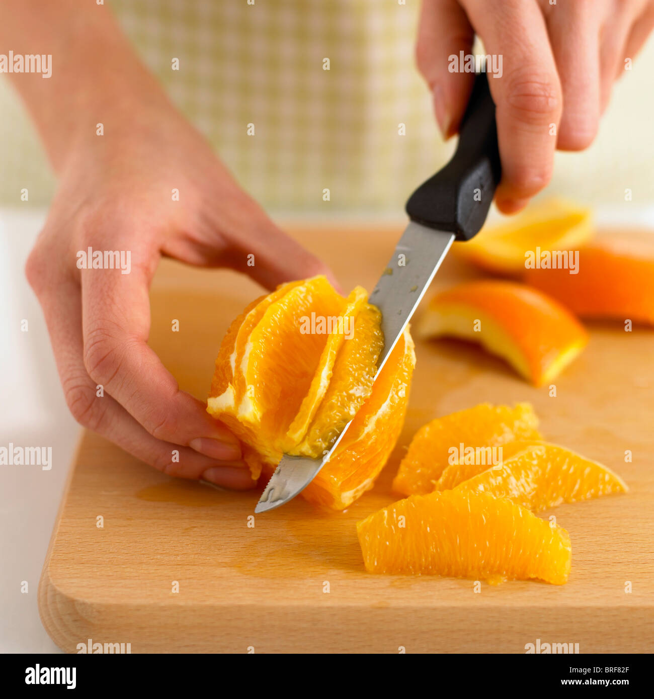Femme à l'aide de couteau pour segmenter une orange Banque D'Images