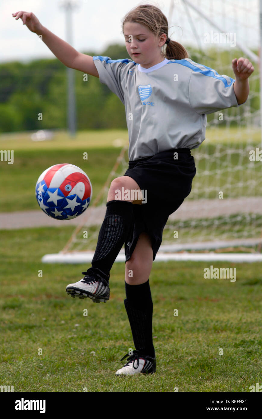 Jeune fille, 10 ans, jonglant avec un ballon de foot Banque D'Images