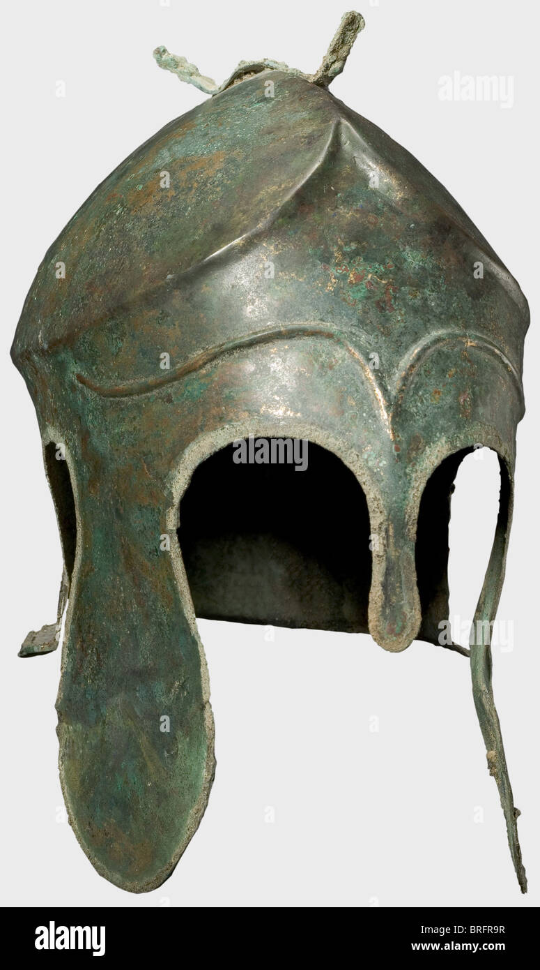 Casque Chalcidien, 5e siècle B.C.Bronze. Crâne allongé étroit avec couronne sculptée et crêtée, fixation en forme de fourche pour le panache du casque, grandes pièces de joue lobé et découpes d'oreilles, et une protection de cou à évasement court. Le front avec de longs sourcils décoratifs en relief. Le rebord du casque a conservé une partie du bord soudé (brasure en brasure Placez tout autour). La joue gauche est courbée vers l'extérieur avec une perforation sévère, probablement à partir de l'offre votive du casque dans un sanctuaire.hauteur 19.5 cm.poids 638 g.le métal est bien-pr, droits supplémentaires-Clearences-non disponible Banque D'Images