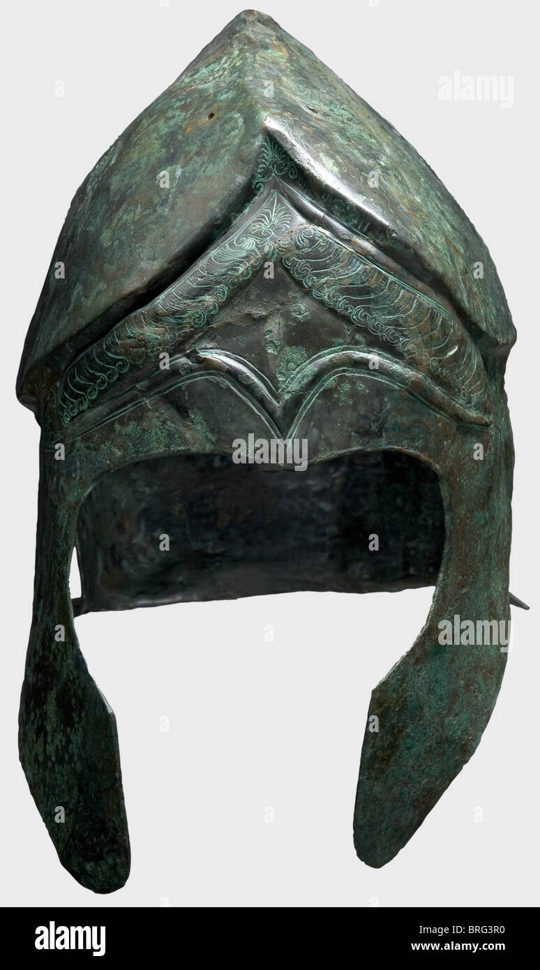 Casque Chalcidien, 5e/4e siècle B.C.Bronze.crâne allongé étroit avec une couronne sculptée et crêtée,trous pour la fixation du panache,grandes pièces de joue et découpes d'oreilles,et une petite protection de cou évasé.le front a des sourcils décoratifs en relief et des palmettos décoratifs richement ciselés,têtes de serpents,serrures de cheveux,et un clou décoratif de joue,vraisemblablement un trou de droite De l'offre votive du casque dans un sanctuaire.hauteur 23 cm.poids 828 g.le métal est déformé, mais bien conservé avec la patine vert foncé.l'interi,droits supplémentaires-Clearences-non disponible Banque D'Images