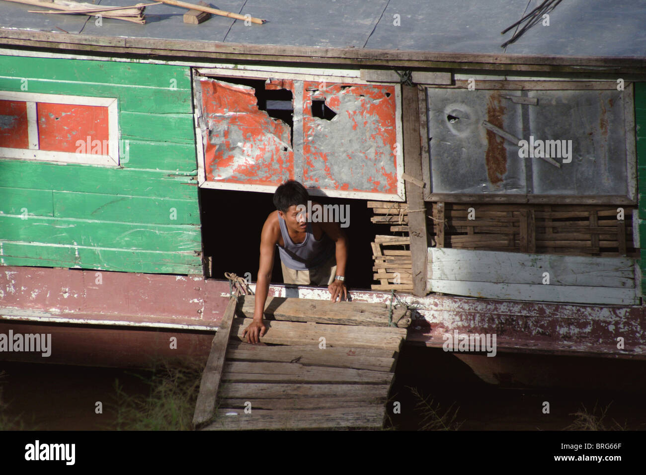 Un homme travaille sur cargo contenant des marchandises exportées de la Chine le long des rives du Mékong à Chiang Sean, en Thaïlande. Banque D'Images