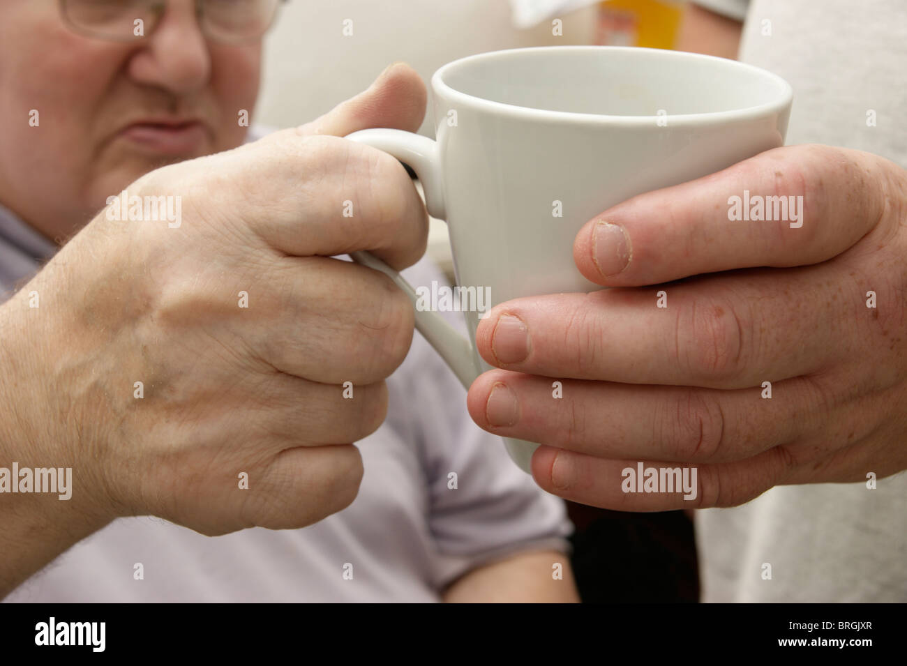 Homme carer (fils) donnant un verre à un vieil homme handicapé Banque D'Images