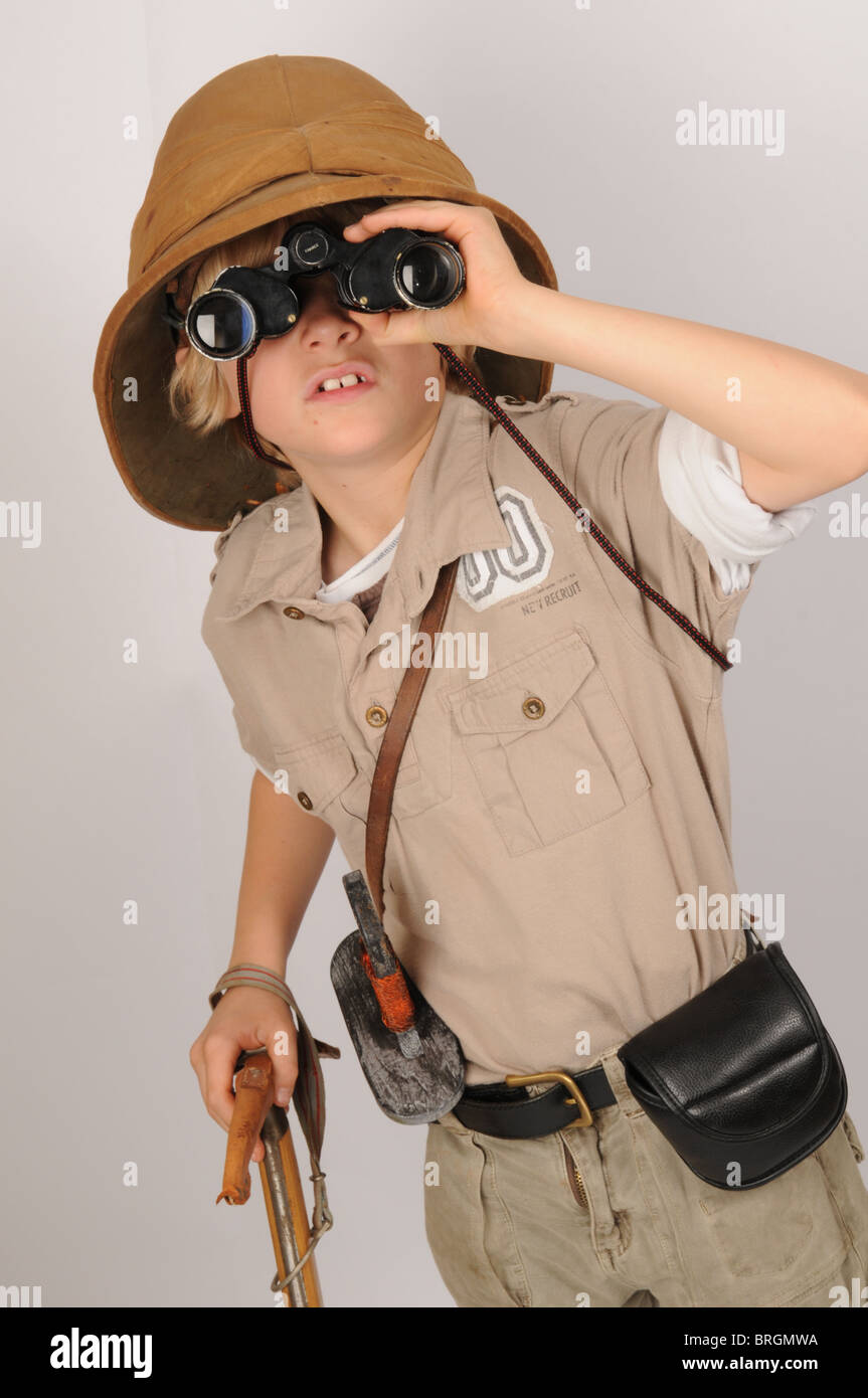 Jeune garçon habillé en prétendre l'explorateur victorien portant un casque colonial regarde à travers des jumelles Banque D'Images