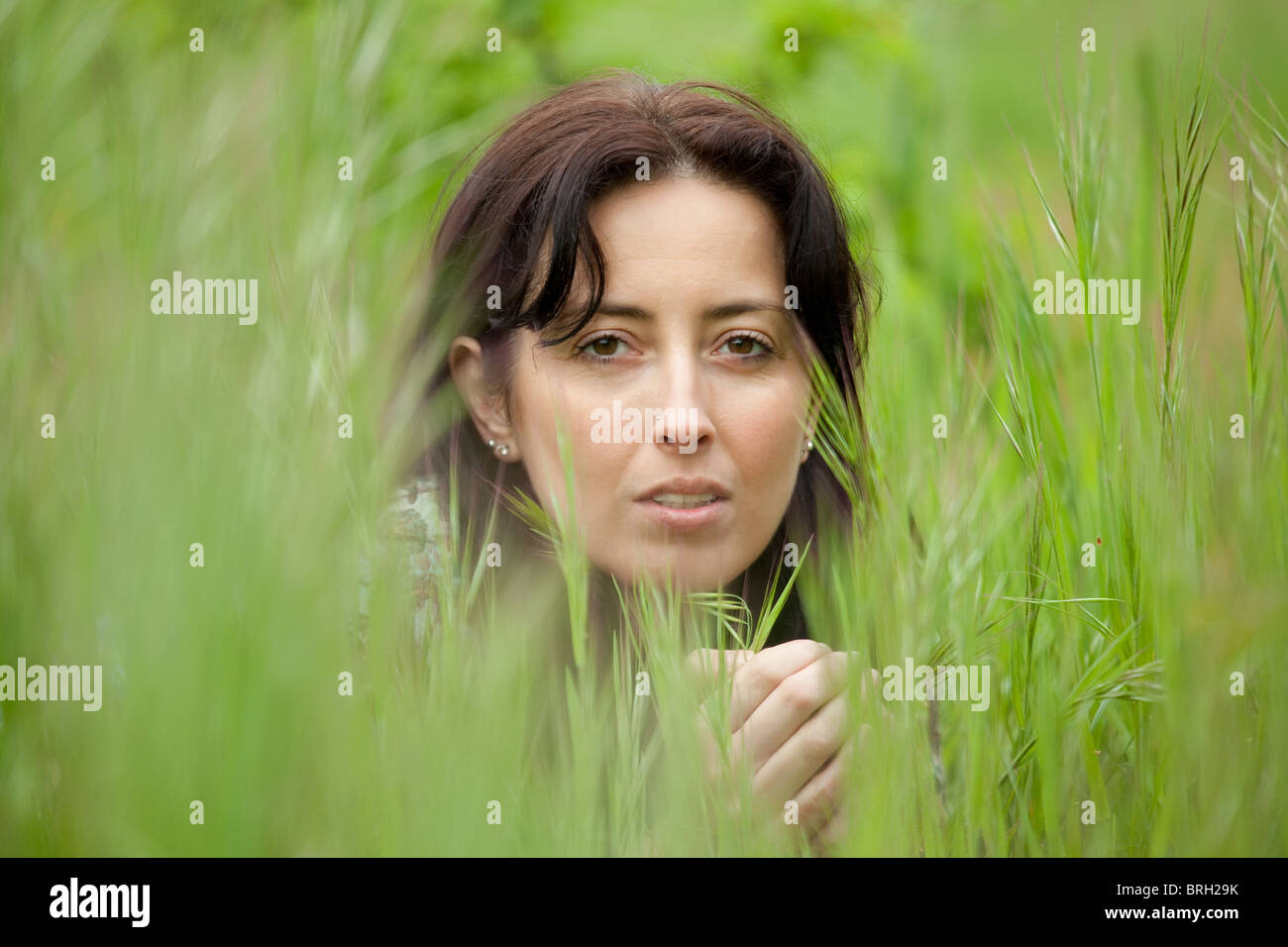 Beautiful woman portrait caché dans l'herbe de lame Banque D'Images