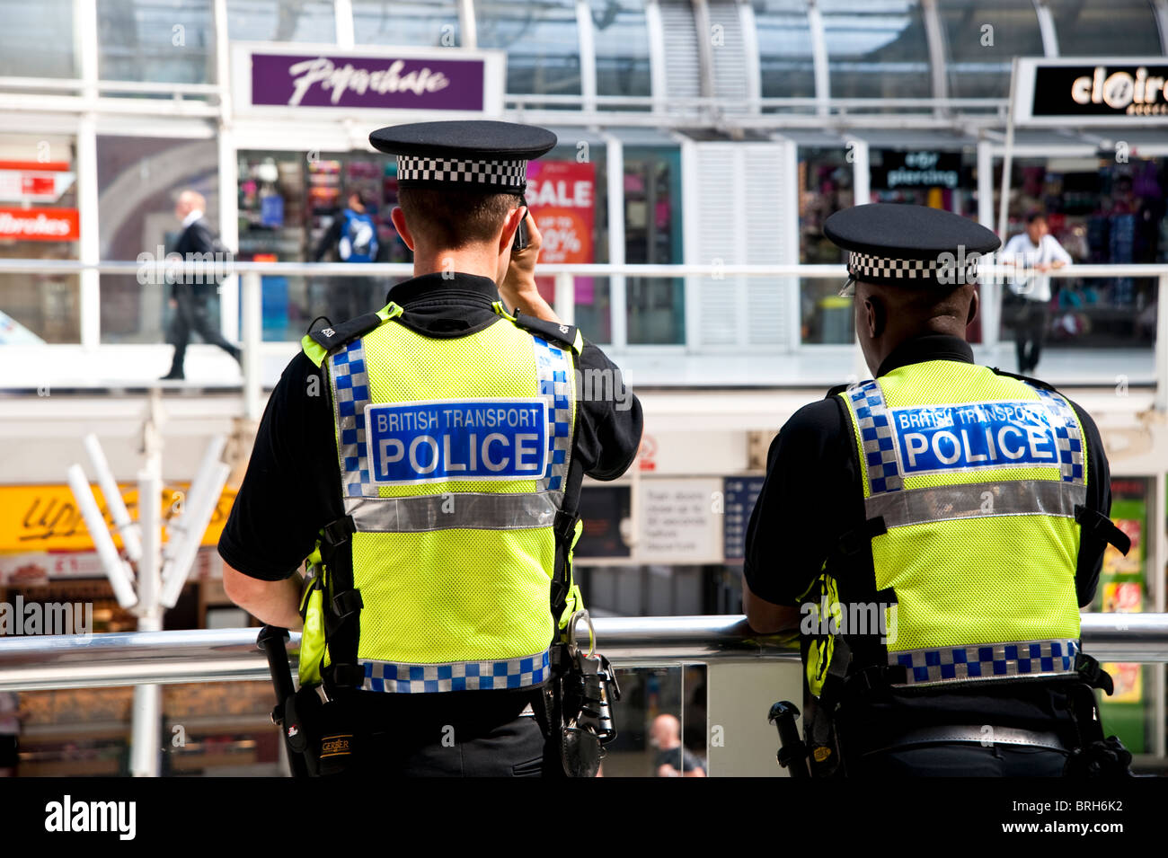 Deux agents de la police britannique des transports navetteurs regarder ci-dessous lorsqu'ils passent par la gare de Liverpool Street dans la ville de Londres. Banque D'Images